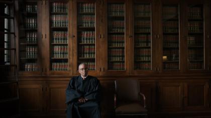 Judge seated in library before legal books