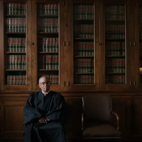 Judge seated in library before legal books