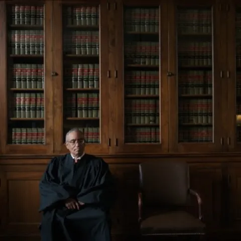 Judge seated in library before legal books